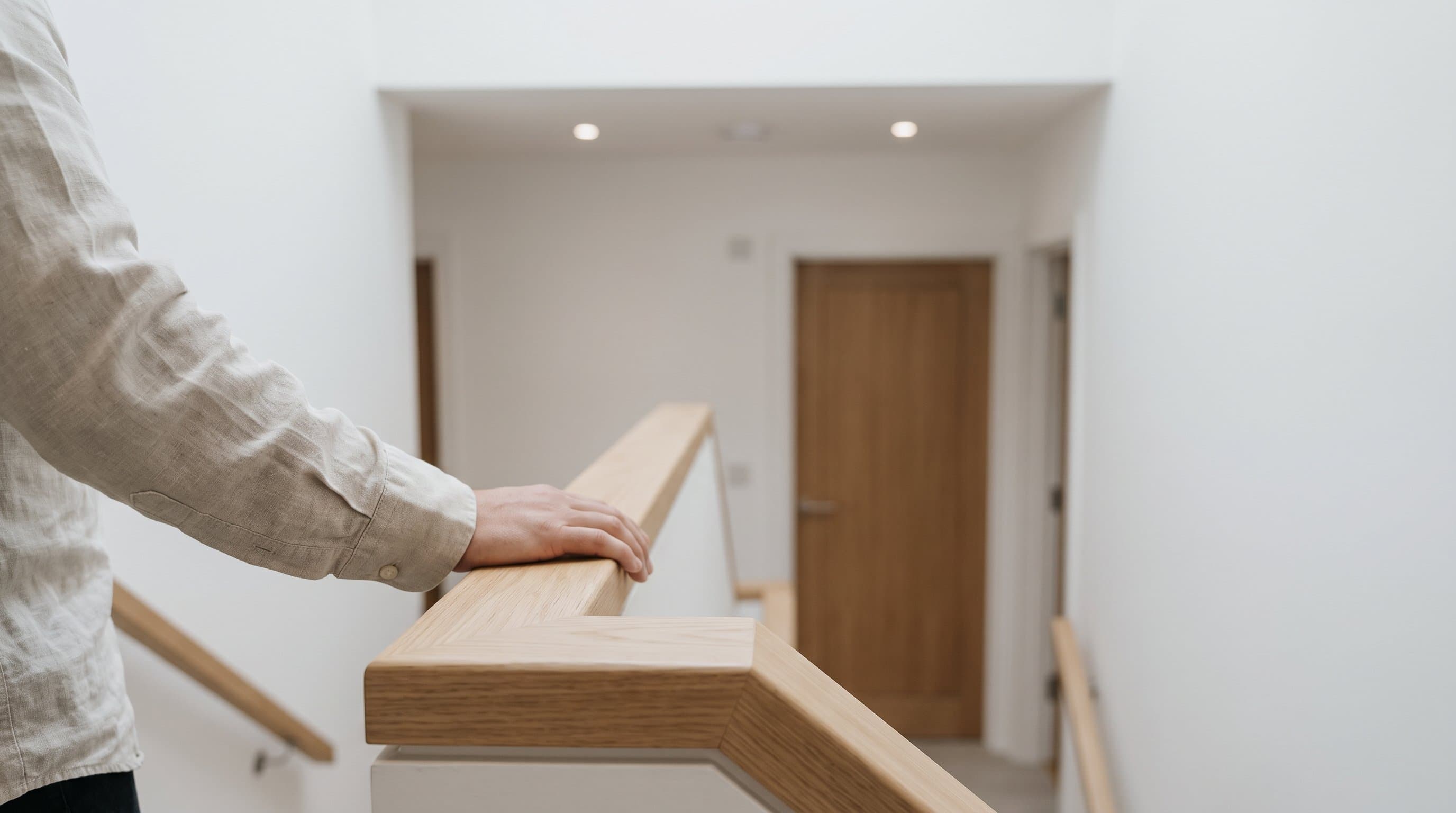 Eine neue Massivholztreppe aus Eiche, eine Hand auf dem glatten Handlauf